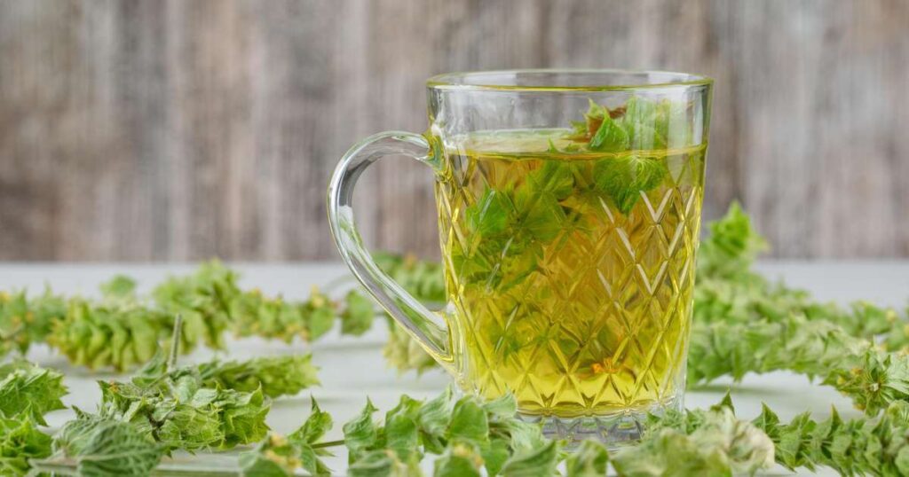 Chá de salsinha em uma xícara com folhas frescas de salsinha ao lado