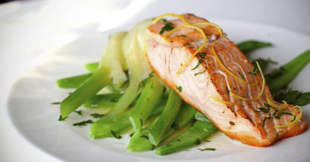 Prato colorido com alimentos da dieta nórdica, incluindo peixes, vegetais, frutas vermelhas e grãos integrais.